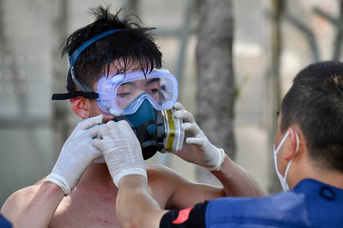 A volunteer is helped out of his face mask after disinfection in Xiamen, one of the city’s in China's southeastern Fujian province, which is battling to control an outbreak of the Covid-19 Delta variant. Photo: Xinhua