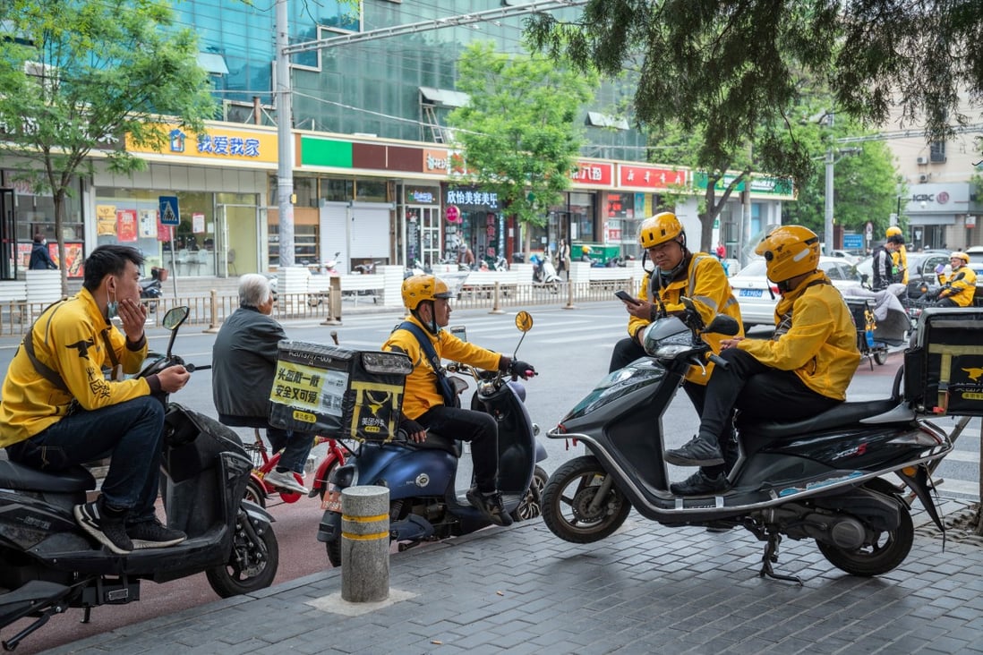 Food delivery couriers for Meituan gather around motorcycles in Beijing on April 21. Photo: Bloomberg