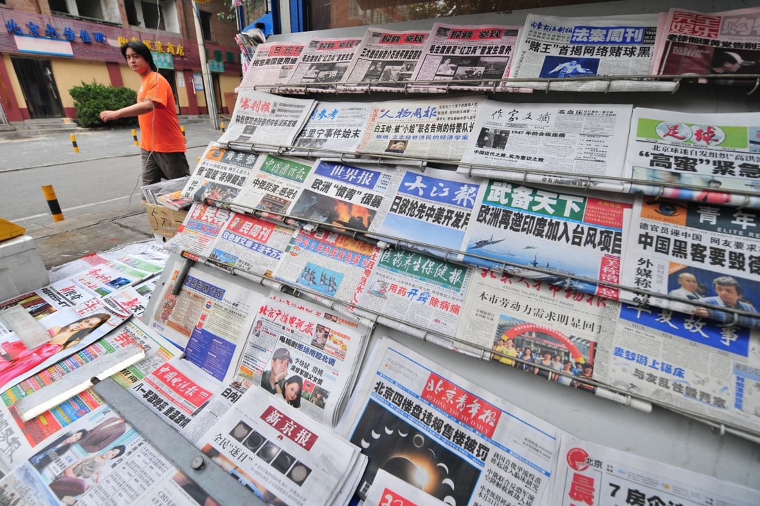A man walks past a display of newspapers at a news-stand in Beijing on July 23, 2009. In a new draft document reiterates rules in place since 2005 banning private capital in news media, which the government has previously selectively enforced. Photo: AFP