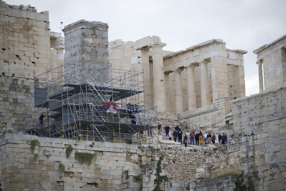 Tsela Zoksang and Joey Siu unfurl banners on scaffolding in the Acropolis on Sunday. Photo: Students for a Free Tibet