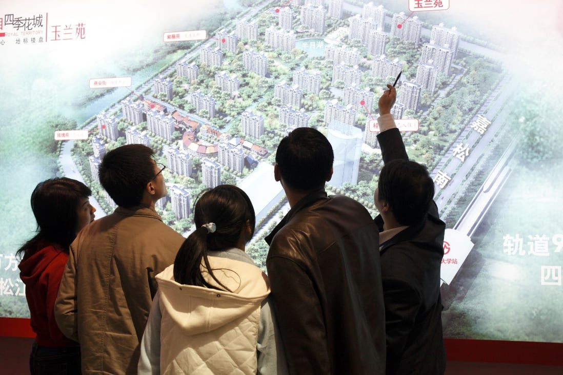 An agent showing the layout of a new residential development at a real estate fair in Shanghai on 15 March, 2009. Photo: Corbis via Getty Images.