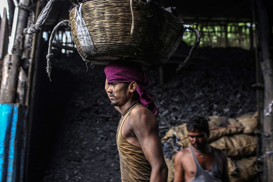 A worker carries a basket of charcoal at wholesale market in Mumbai, India. India, the third-biggest emitter of greenhouse gases, still relies on coal for about 70 per cent of electricity generation. Photo: Bloomberg
