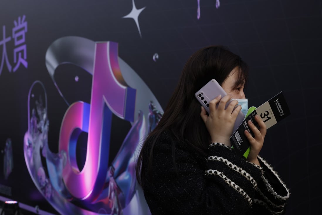 A woman speaks on her phone near a Douyin logo in Beijing on March 31, 2021. Photo: AP Photo