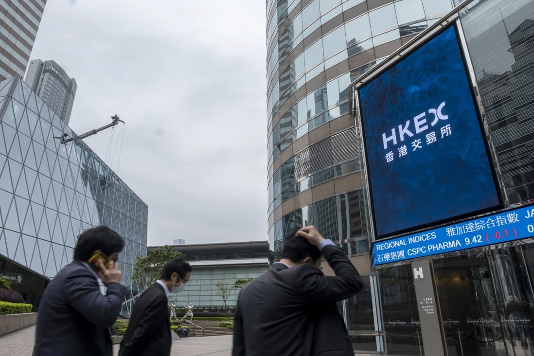 People walk past an electronic board showing the Hang Seng Index and stock tickers in Central, Hong Kong. China’s economic slowdown is sapping risk appetite. Photo: Bloomberg