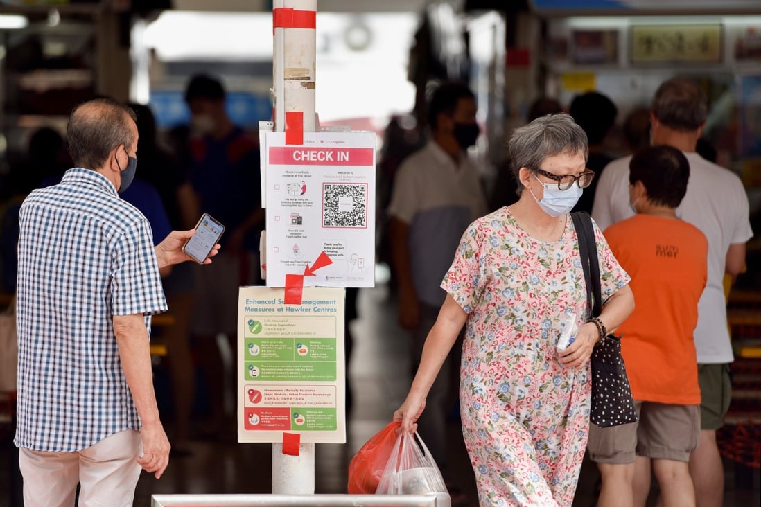 A man entering a food centre checks in on his phone before being allowed to dine in, as part of Singapore’s coronavirus restrictions. Photo: Reuters