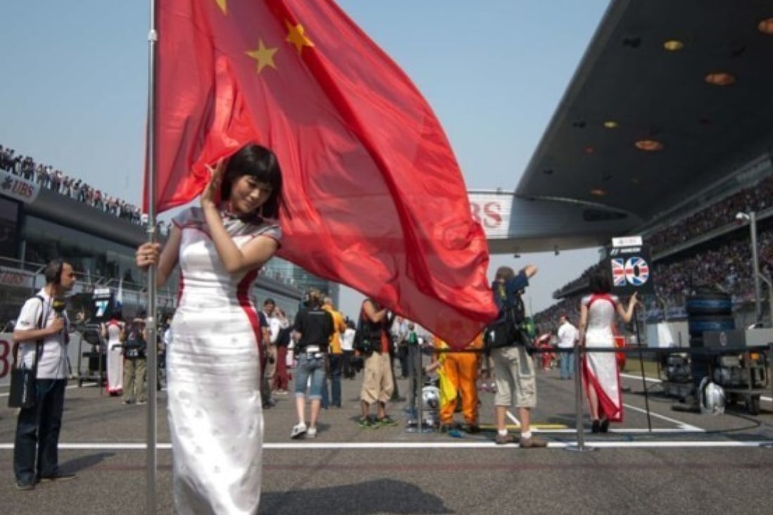 A grid girl holds a Chinese flag as she stands on the starting grid for the 2013 Formula One Chinese Grand Prix in Shanghai. Photo: AFP