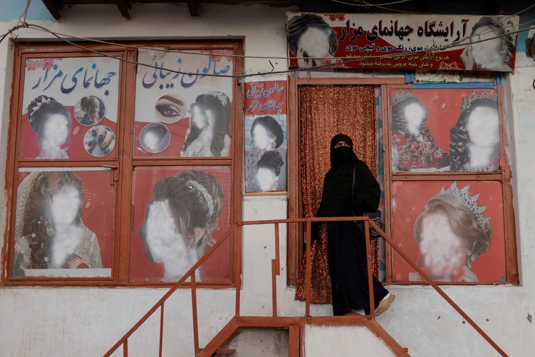 A woman wearing a niqab enters a beauty salon where the adverts of women’s hairstyles have been defaced by a shopkeeper in Kabul, Afghanistan. Photo: Reuters