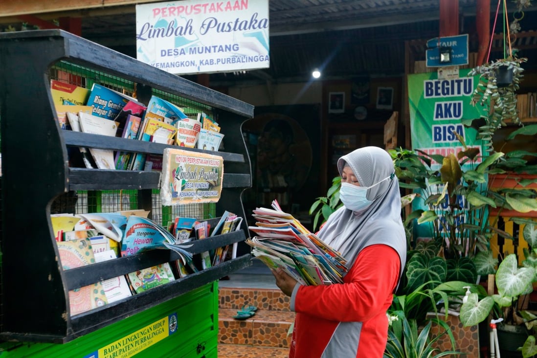 Raden Roro Hendarti, founder of the Limbah Pustaka (trash library) arranges books on her three-wheeler vehicle. Photo: Reuters