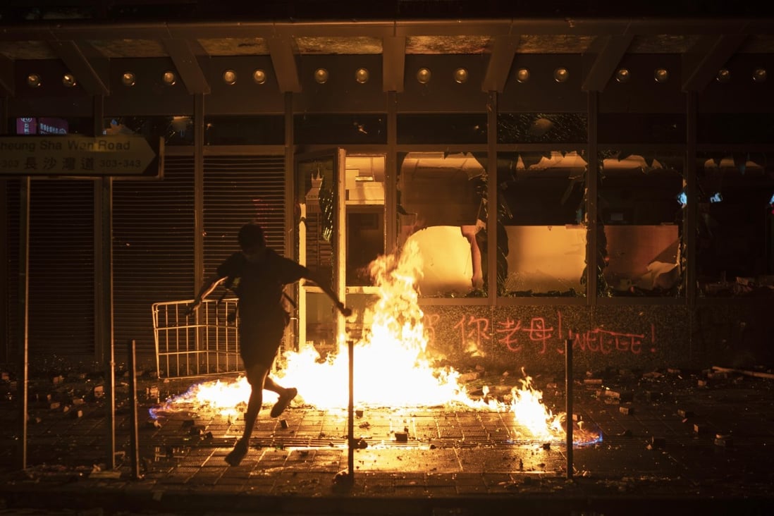 A protester runs after setting a government office building on fire in Hong Kong, in October 2019. Photo: AP