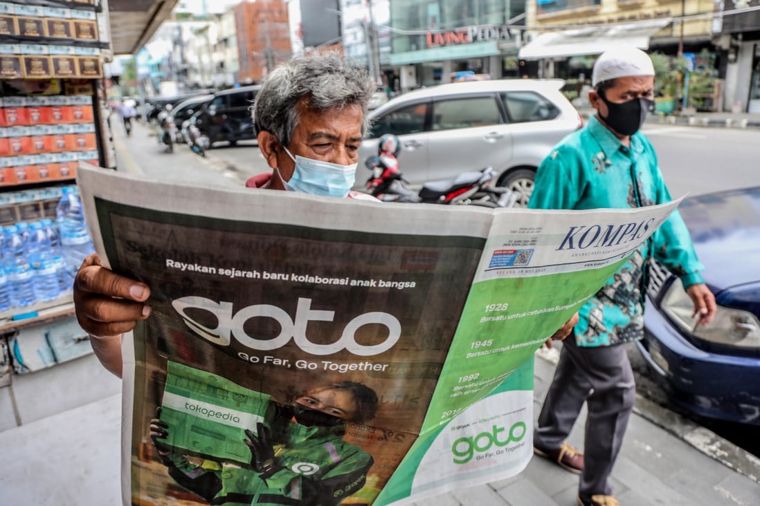 A man reads a newspaper with an advertisement heralding the merger between Gojek and Tokopedia into GoTo Group in May. Photo: EPA-EFE