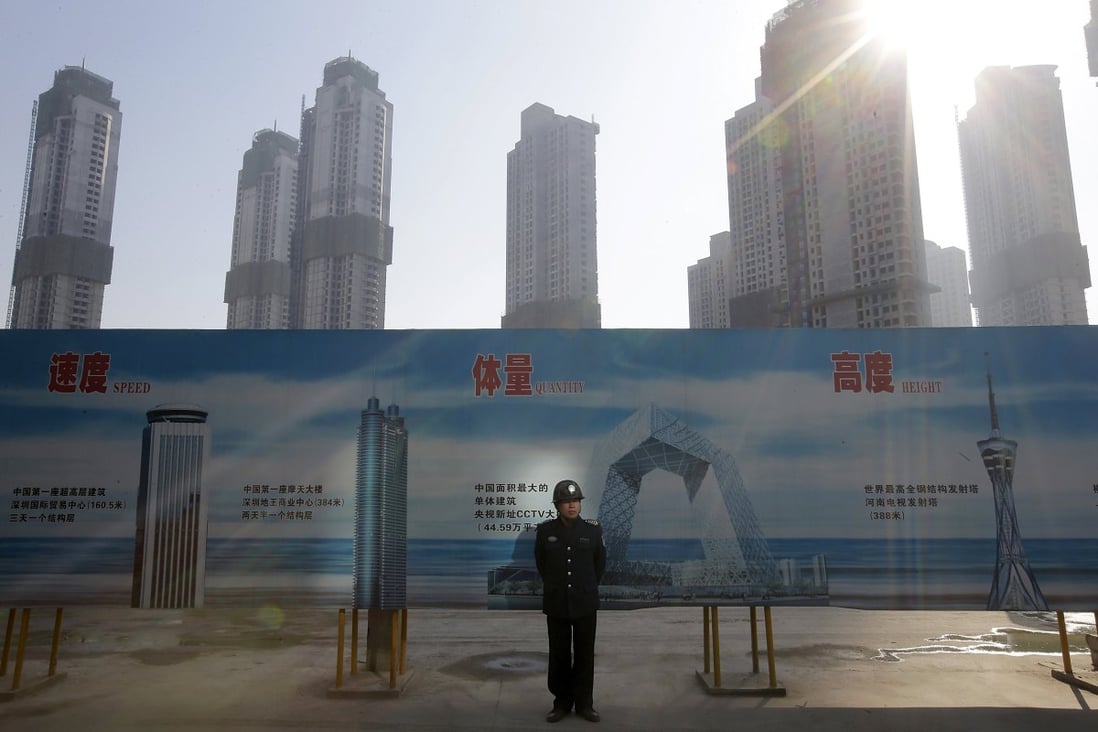 A security guard stands next to an advertising board in front of a residential compound under construction in Wuhan, Hubei province. Photo: Reuters