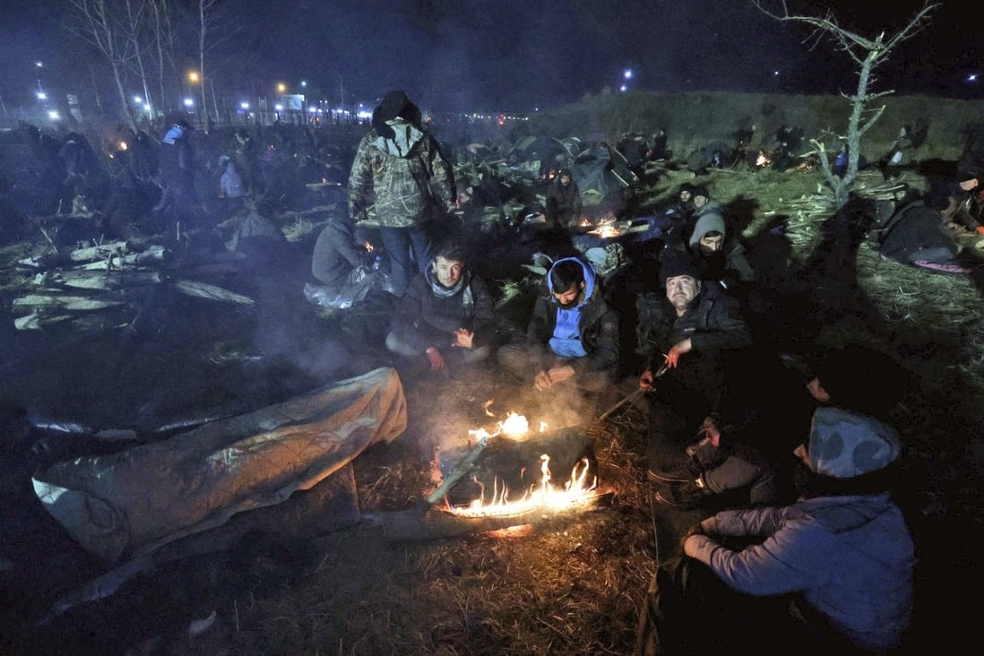 Migrants warm themselves by a fire at the Belarus-Poland border near Grodno, Belarus, on Tuesday. A Polish government official said on Wednesday that people who have spent days in a makeshift camp were being taken away by bus by Belarusian officials, offering the prospect of a possible de-escalation in a tense stand-off. Photo: BelTA via AP