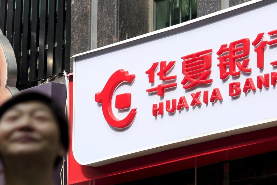 A woman speaks on her mobile phone as she walks past a Hua Xia Bank branch in Shanghai on October 9. Photo: Reuters