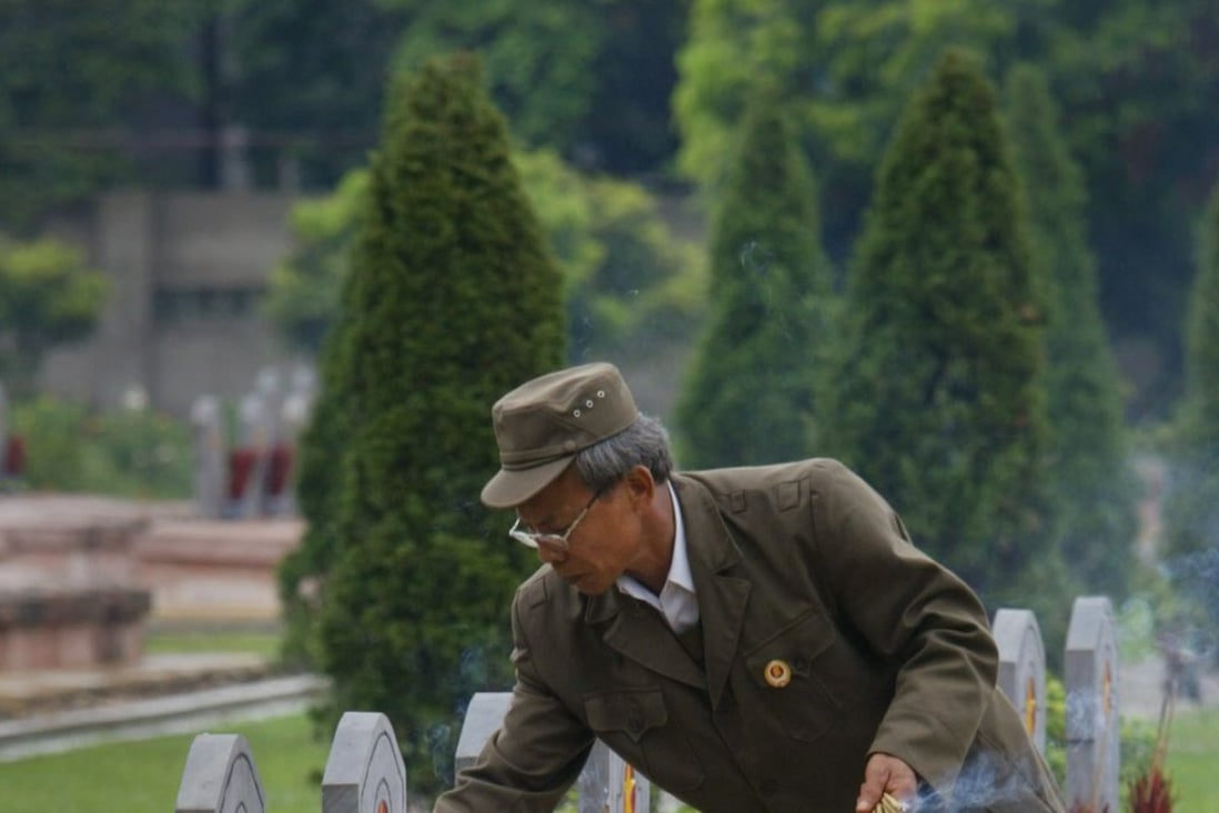 A Vietnamese war veteran places incense on graves of dead soldiers in Dien Bien Phu. Photo: Reuters
