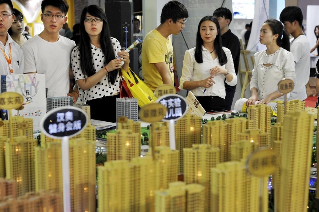Sales representatives talk to potential buyers in front of a model of a residential complex at a real estate exhibition in Wuhan, Hubei province, China. Photo: Reuters