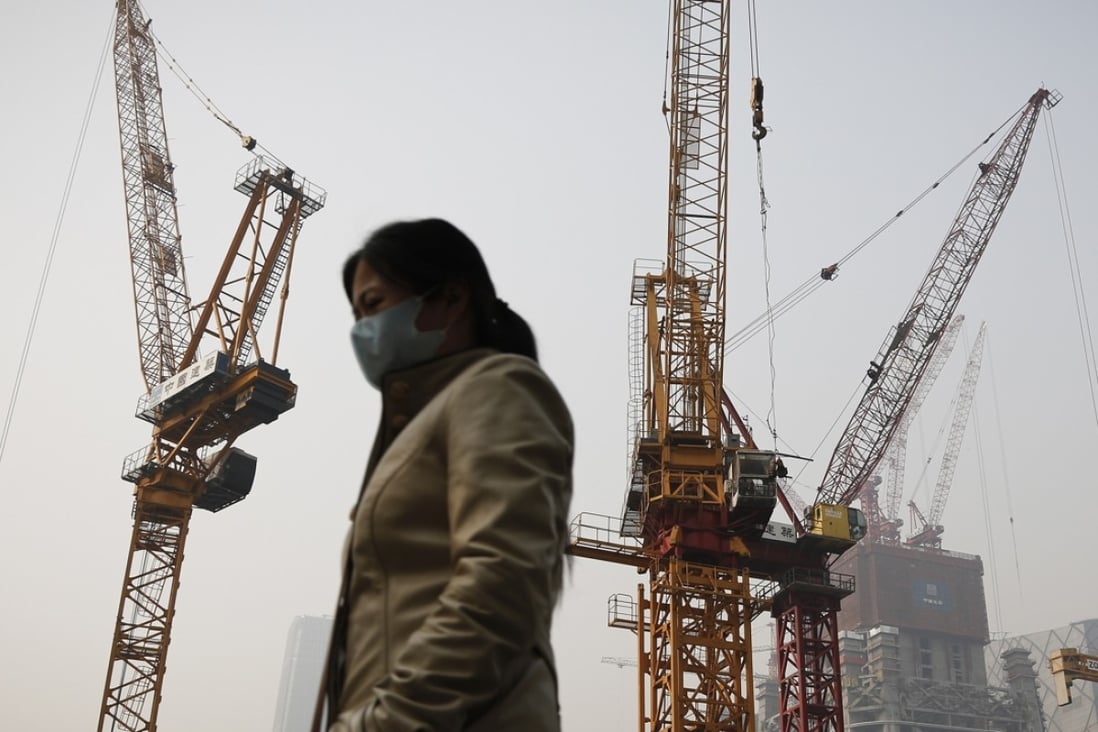 A woman strolls past a construction site in Beijing, China, as the rate of construction in the country is expected to fall to historical lows. Photo: AP