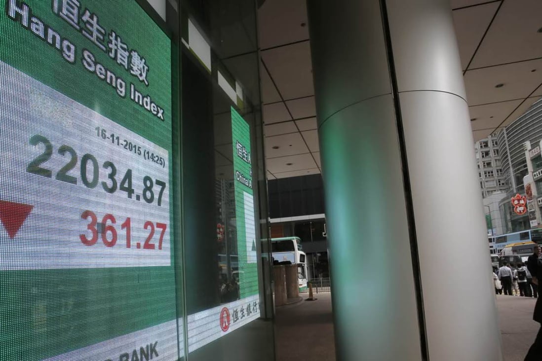 A man walks past a bank electronic board showing the Hong Kong share index in Hong Kong. Markets may trend quiet during this week when the US markets will be shut Thursday for Thanksgiving. Photo: AP