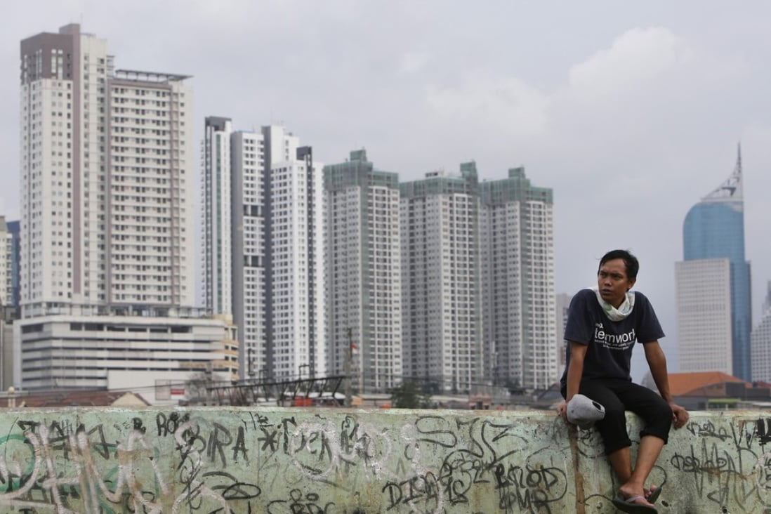 A man sits on a wall with the skyline of the main business district as a backdrop in Jakarta on November 24. Photo: AP