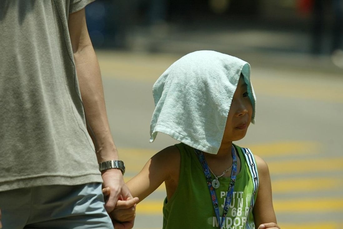 A child covers his head against the strong sunlight. The heatwave in Hong Kong reached 34 degrees in the afternoon. 18 July 2005