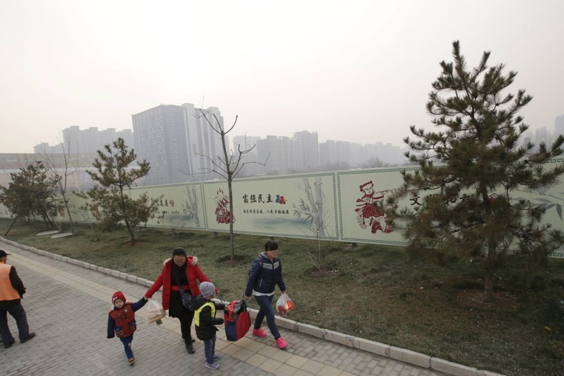 Residents walk past a wall surrounding an empty field, which was purchased by a Chinese real estate developer for 3.3 billion yuan in November. Photo: Reuters