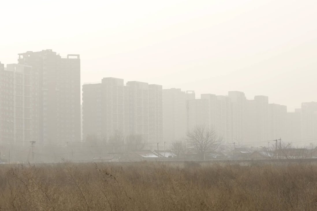 Residential buildings are seen behind an empty field which was purchased by a Chinese real estate developer for 3.3 billion yuan (US$515 million) in November, on a hazy day in Beijing. Photo: Reuters