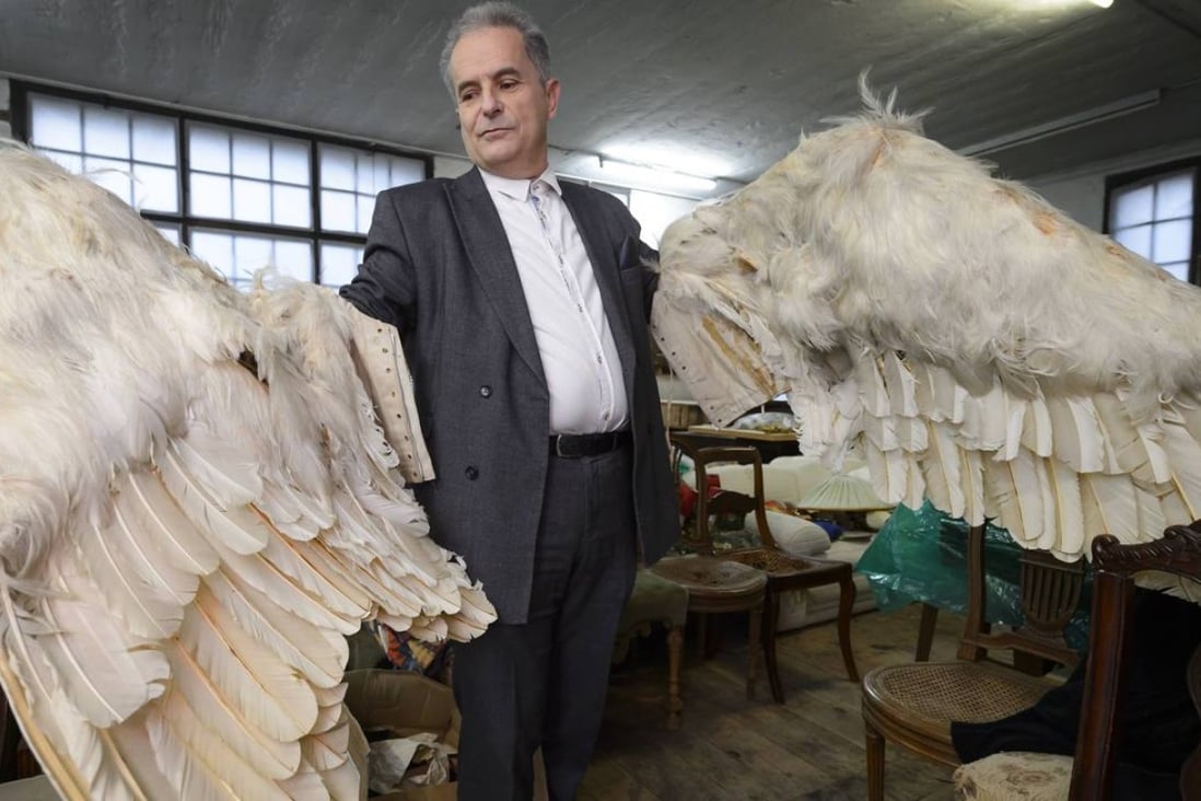 Swiss author Pierre Smolik poses with crafted wings covered with swan feathers made for a final film by comic actor and filmmaker Charlie Chaplin that was never completed. Photo: AFP