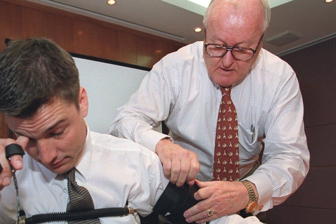 A former Federal Bureau of Investigation (FBI) agent (right) demonstrates a polygraph test on a volunteer, with sensors attached to his fingers, arm and chest. Photo: Garrige Ho