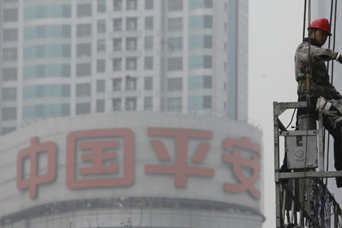 A worker cleans the windows of a building in front of the Ping An Insurance building in Shanghai. Photo: Reuters