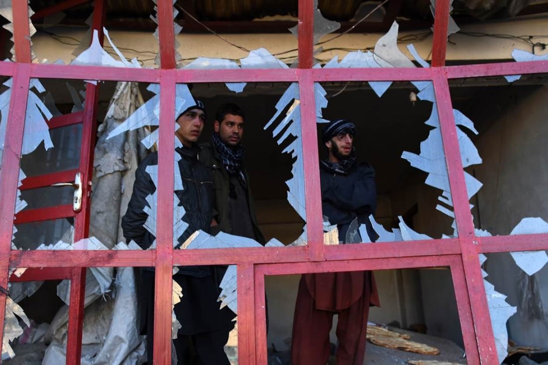 Afghans peer through the broken windows of a bakery at the site of a suicide car bomb blast near the international airport in Kabul on Monday that killed one person. Photo: AFP