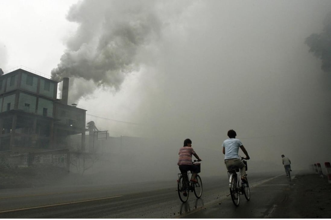 Cyclists pass through thick pollution from a factory in Yutian in China's northwest Hebei province. Photo: AFP