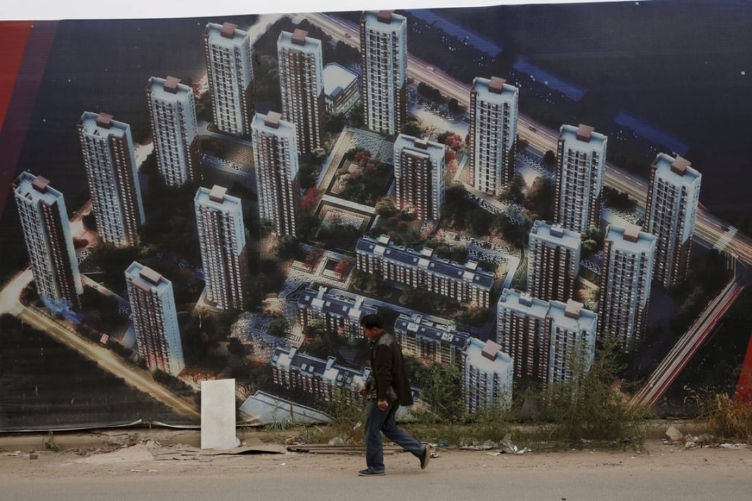 A man walks past a wall at a construction site for a new residential compound in Tianjin’s Binhai new district. Photo: Reuters