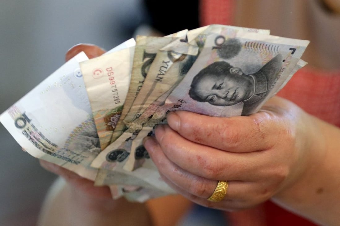 A vendor holds yuan notes at a market in Beijing. Photo: Reuters