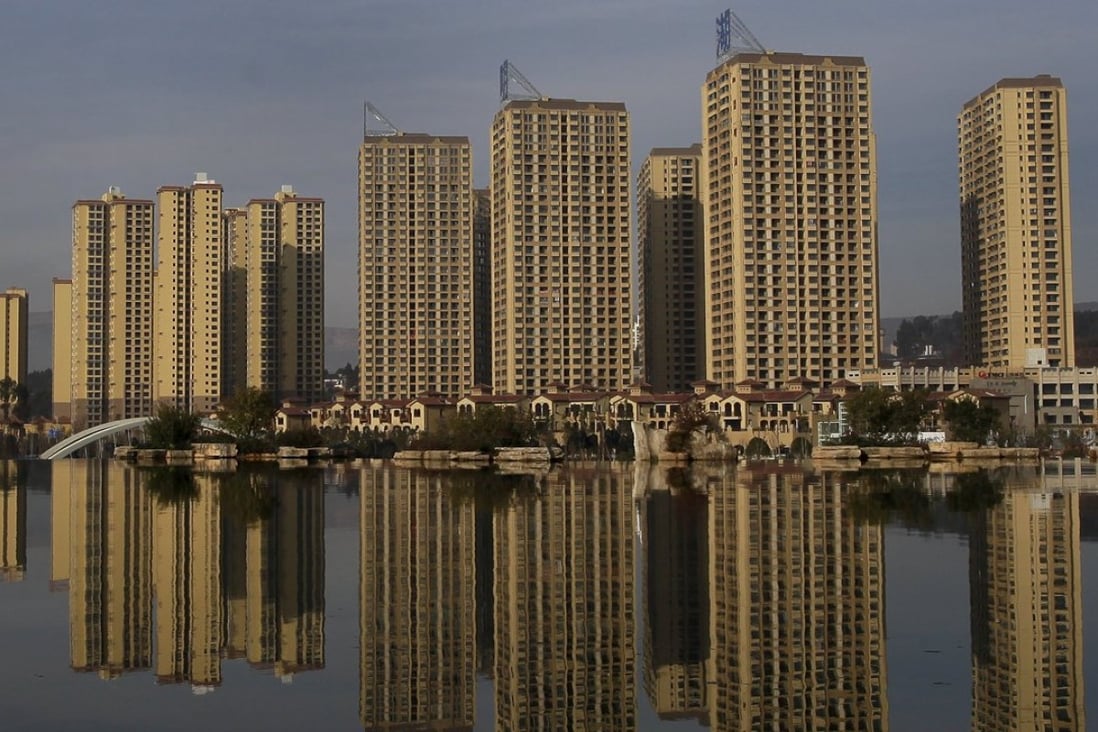 Newly constructed residential buildings are seen reflected in an artificial lake at Kunming Waterfall Park, Yunnan Province, China, in this January 14, 2016 file photo. Photo: Reuters