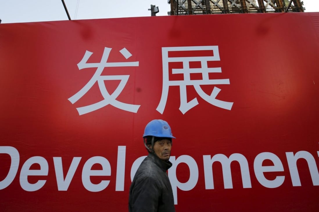 A worker walks past a propaganda slogan on a wall at a construction site in Beijing. Photo: Reuters