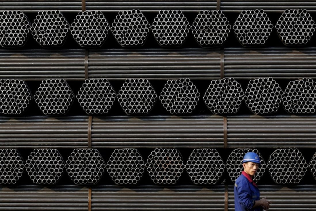 A worker walks past a pile of steel pipe products at the yard of a steel pipe plant in Tangshan, Hebei province. The city is China’s steel production capital. Photo: Reuters