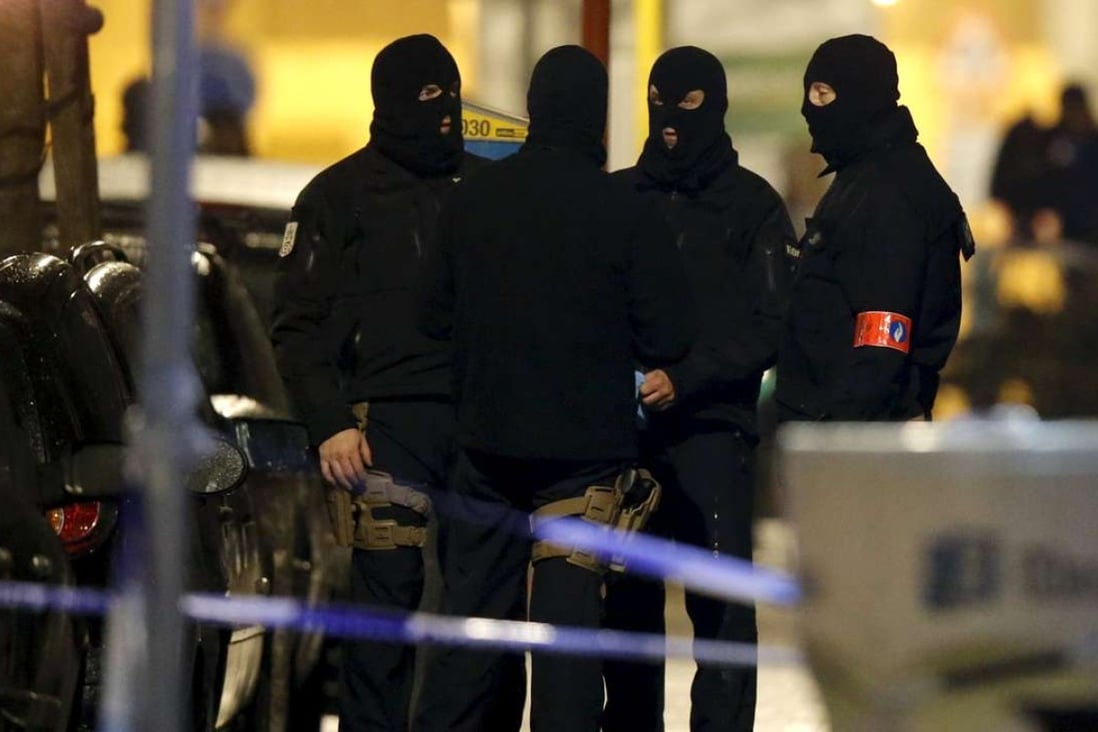 Masked Belgian police secure the entrance to a building in Schaerbeek in Brussels early on Friday. Photo: Reuters