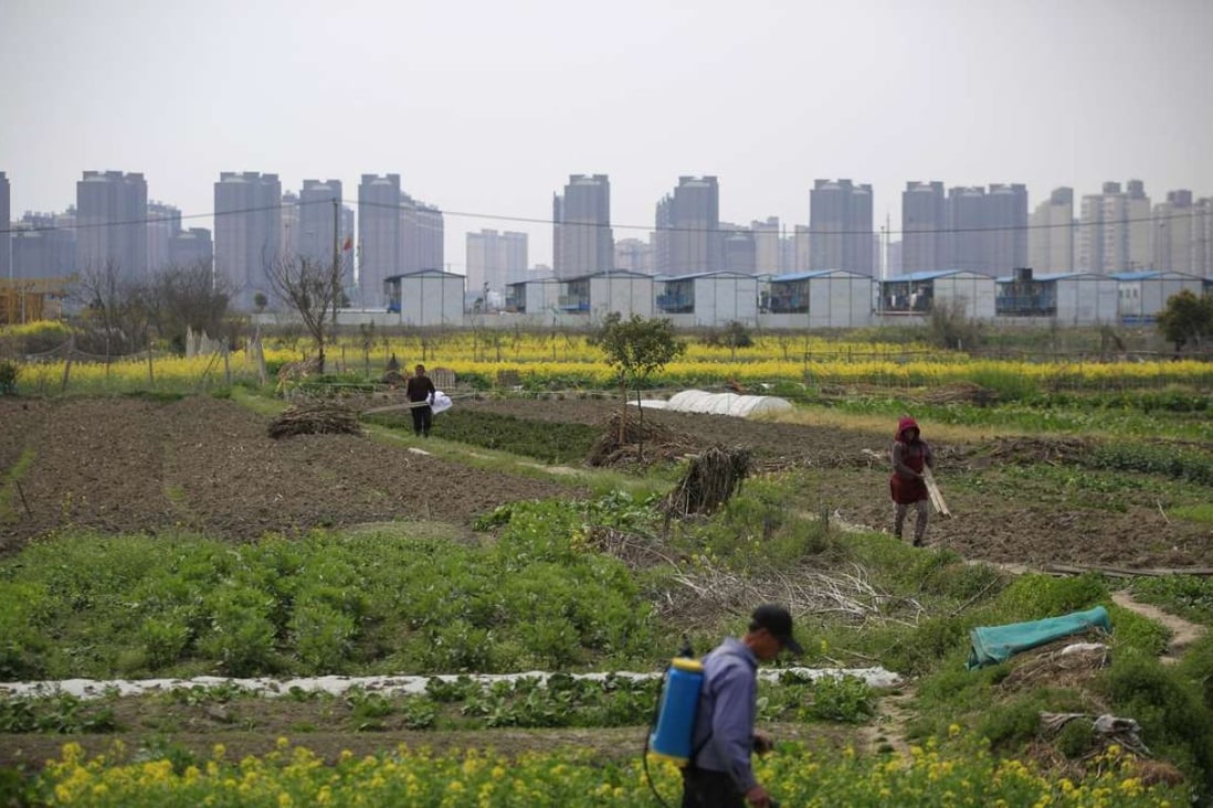 A farmer works on a farm in front of a construction site of new residential buildings in Shanghai on March 21, 2016. Photo: Reuters