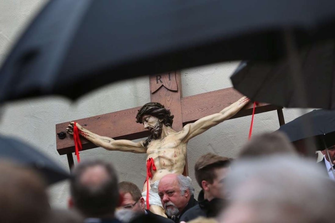Members of the Mason's Guild in front of a figure of Jesus with red ribbons representing stigmata at a Good Friday procession through the city centre of Lohr am Main in Germany. Photo: EPA