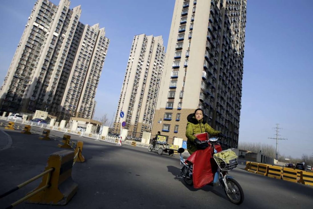A woman rides past a residential compound in Beijing's Tongzhou district. Photo: Reuters