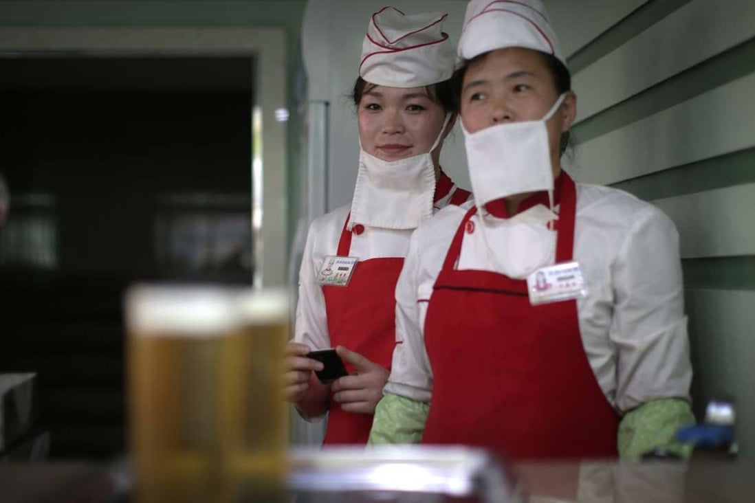 Beer servers Kim Yon-hui, 29, left, and Yang Pok-yong, 42, right wait to serve customers at the Taedonggang Beer shop in Pyongyang, North Korea. Photo: AP
