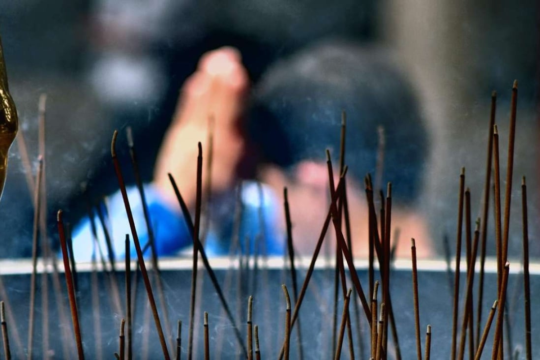 A man prays behind burning incense at Lung Shan Temple in Taipei. Some temples are asking worshippers to stop burning incense and paper offerings to reduce air pollution. Photo: AFP