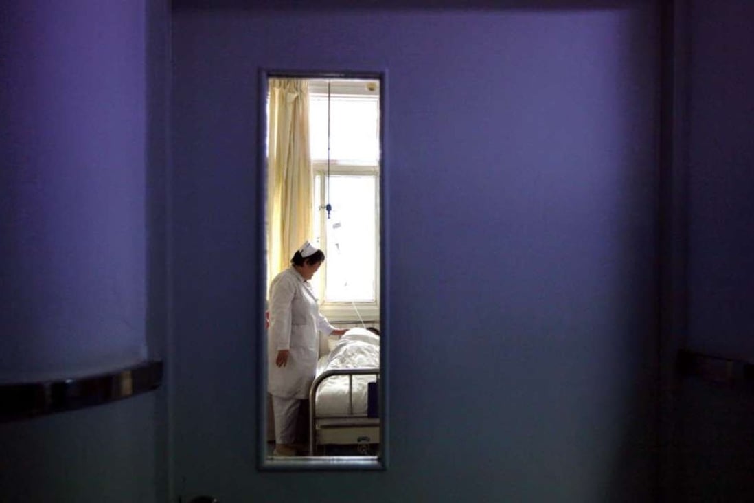 A nurse is seen through a door as she talks to an infected patient in the HIV/Aids ward of Beijing YouAn Hospital. The mainland has no specific laws against employment discrimination, and its regulations on HIV/Aids prevention and control have no penalties for discrimination. Photo: Reuters