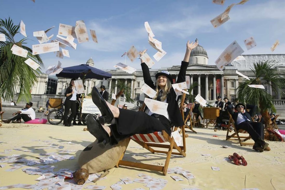 A protester throws fake money into the air in a “tropical tax haven beach” in Trafalgar Square in London. NGOs including Oxfam, Action Aid and Christian Aid are calling for an end to tax havens. Photo: AP