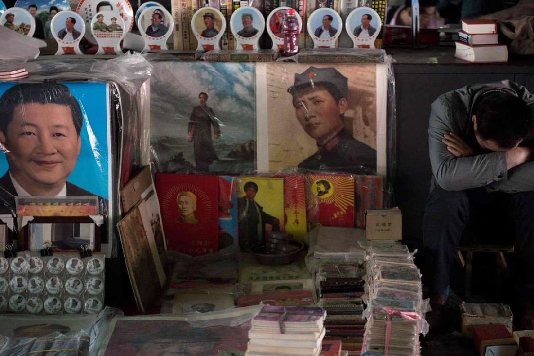 A vendor takes a nap next to posters showing Mao Zedong (centre) and Xi Jinping (left) at a market in Beijing. Photo: AFP