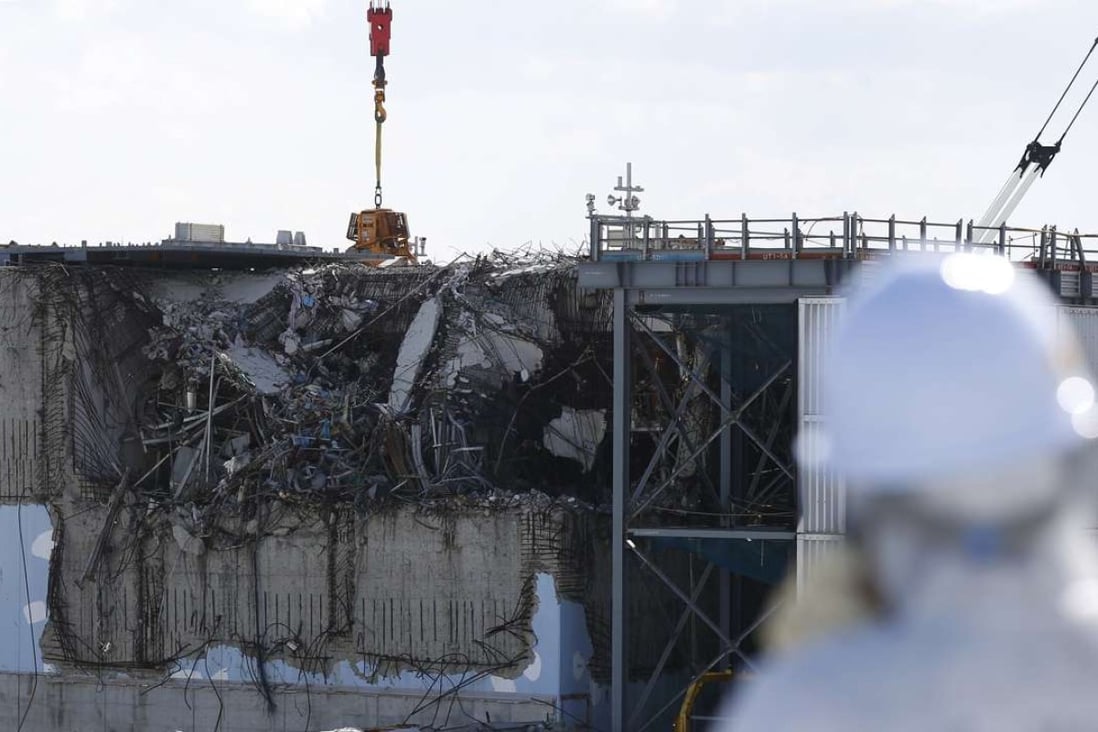 A member of the media wearing a protective suit, looks at the Fukushima Daiichi nuclear power plant. Photo: Reuters