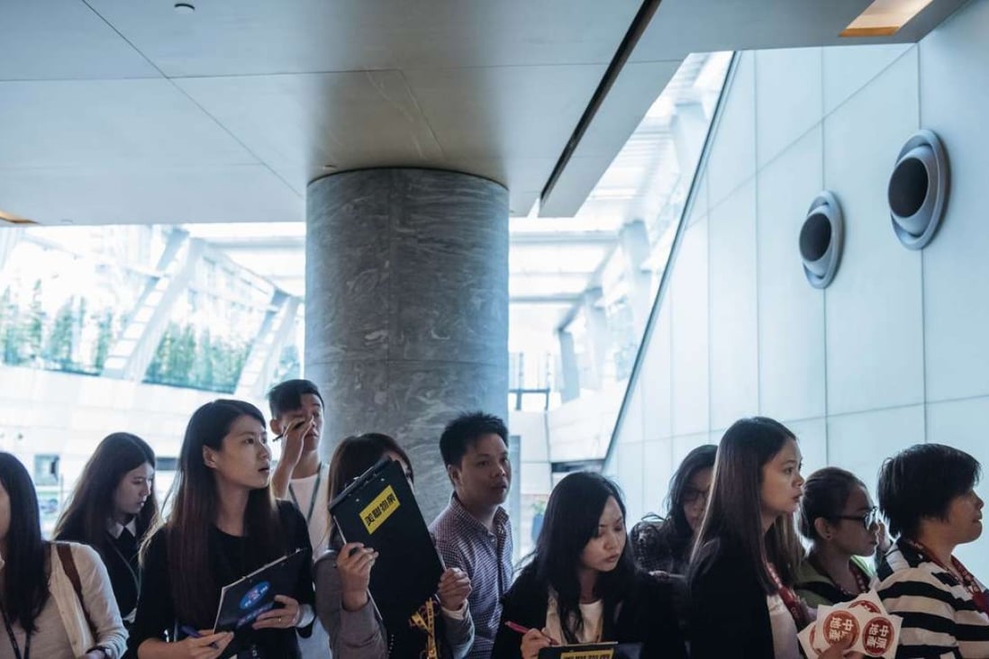 Real estate agents wait for potential buyers outside the sales office of Park Yoho Venezia, a residential property developed by Sun Hung Kai Properties on June 25, 2016. Photo: Bloomberg