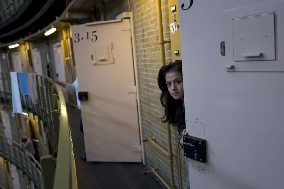 Afghan refugee Shazia Lutfi, 19, peeks through the door of her room at the former prison of De Koepel in Haarlem, Netherlands. Photo: AP