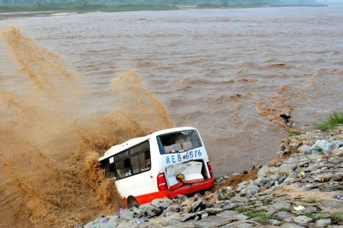 An abandoned bus filled with sand bags is pushed into the river to help shore up the levee outside Xingtai. Photo: Reuters