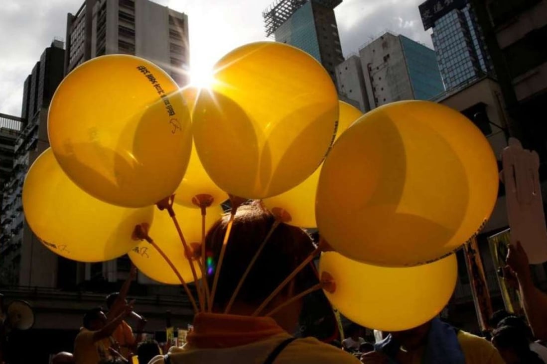 A protestor carries yellow balloons featuring umbrellas, the symbol of the Occupy movement, during a march on July 1. Photo: Reuters