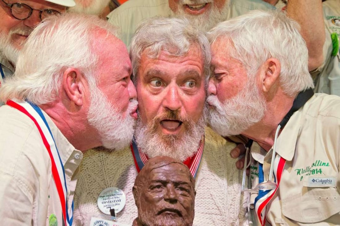 Dave Hemingway (centre) receives smooches from Charlie Boise (left) and Wally Collins after winning the 2016 "Papa" Hemingway Look-Alike Contest in Key West. Photo: Reuters